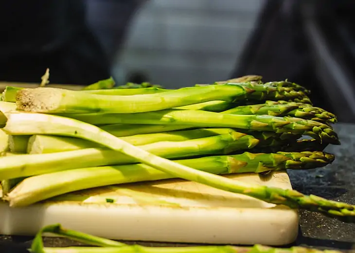 Fresh asparagus displayed on a cutting board in a kitchen setting