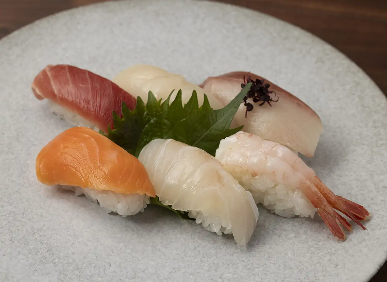 レストランのキッチンで石板に寿司を丁寧に盛り付けるシェフ